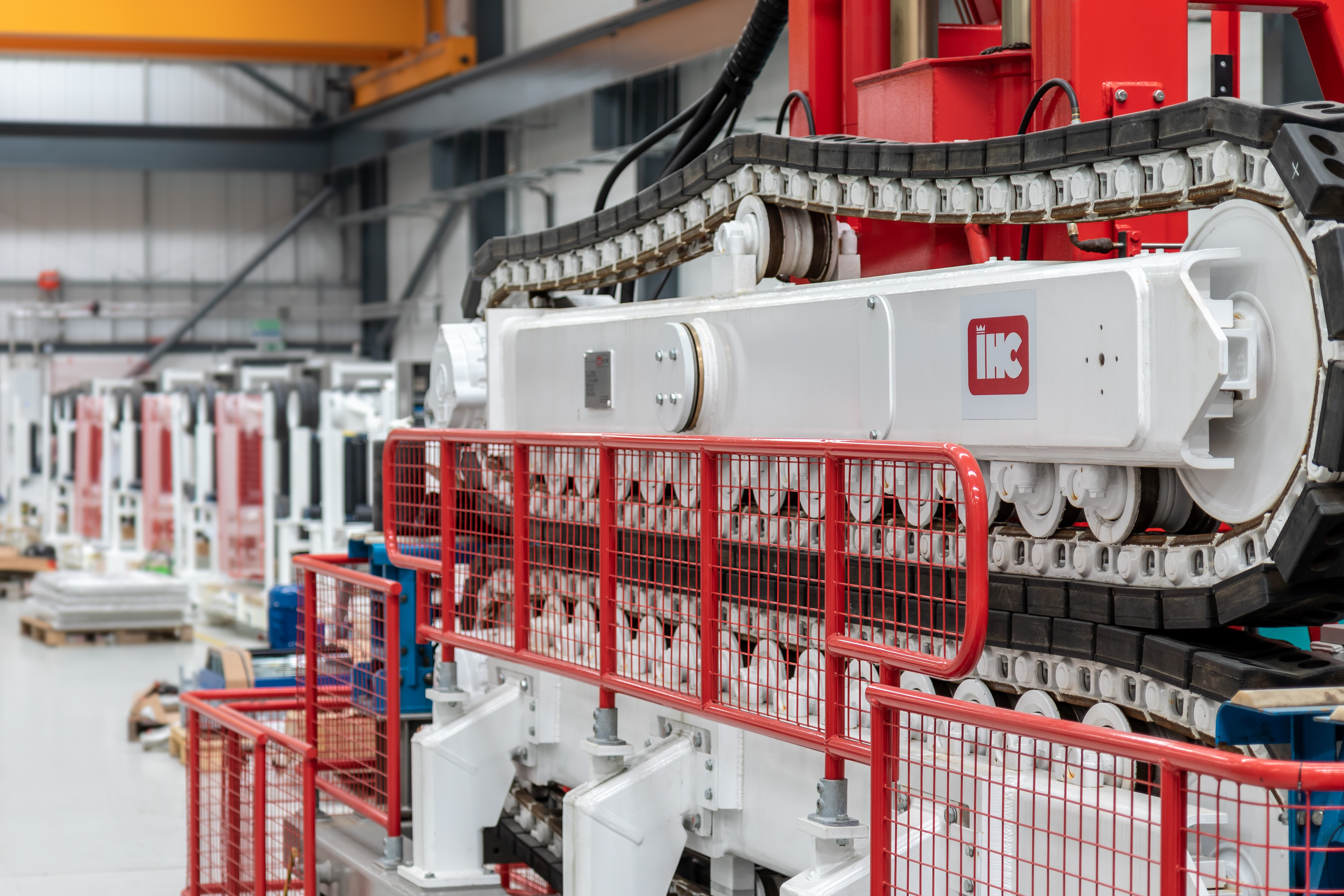 Close up of a red and white two-track cable tensioner in a factory setting.