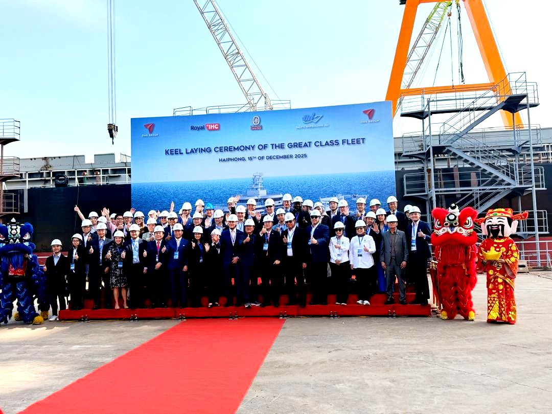 A group of people in hard hats and formal attire are gathered for a group photo at the keel laying ceremony of the GREAT Class Fleet.