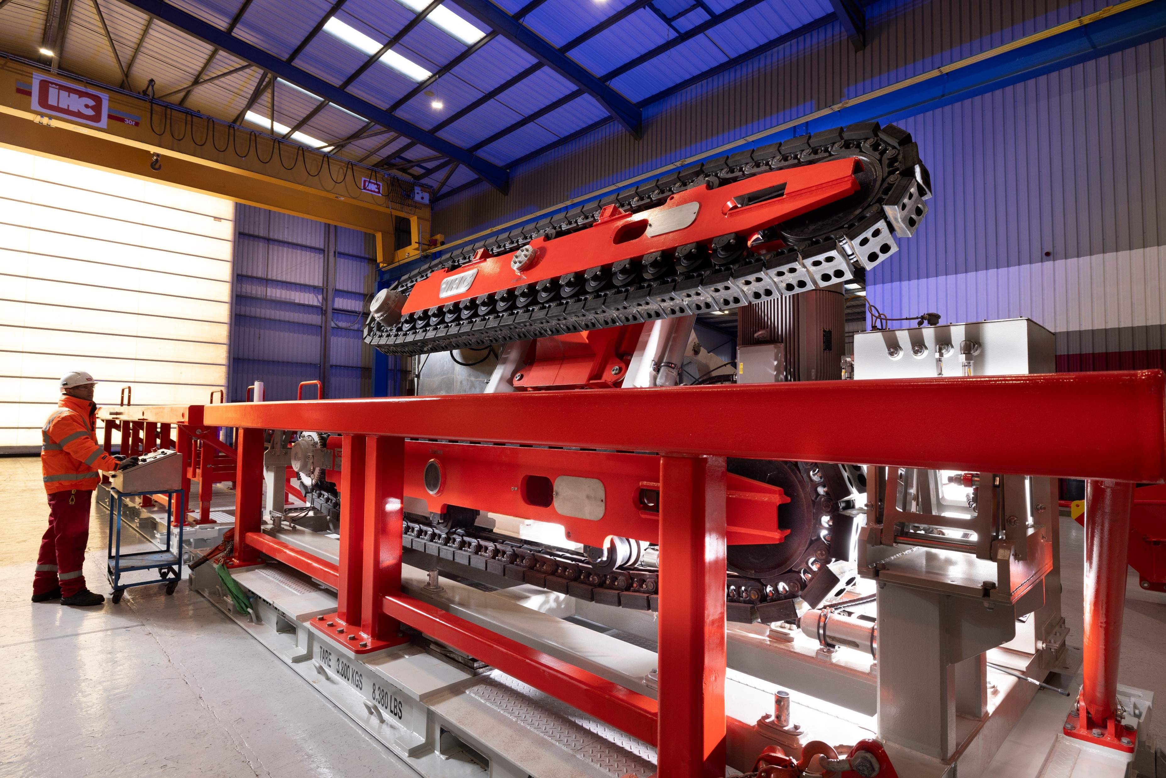 Set in a large factory bay, a red cable tensioner is in breakback position.