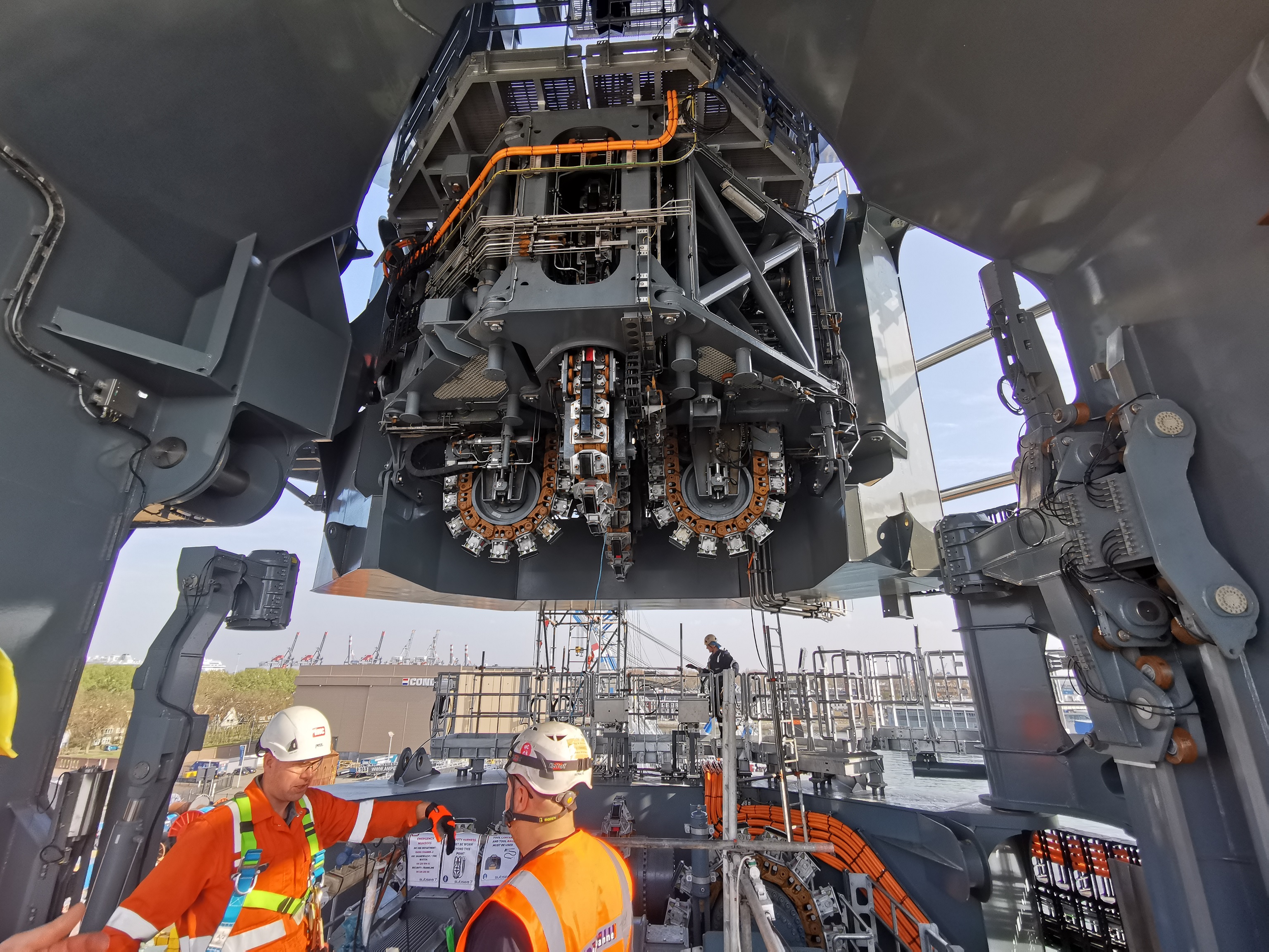 2 engineers in safety gear preparing equipment under a tensioner