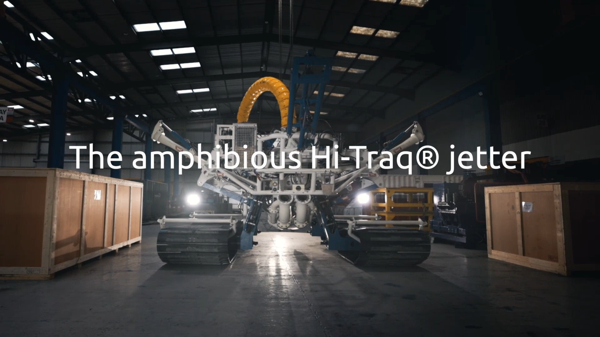 The four-tracked Hi-Traq trencher in a dark factory setting. Text overlaid in white: 'The Amphibious Hi-Traq Jetter